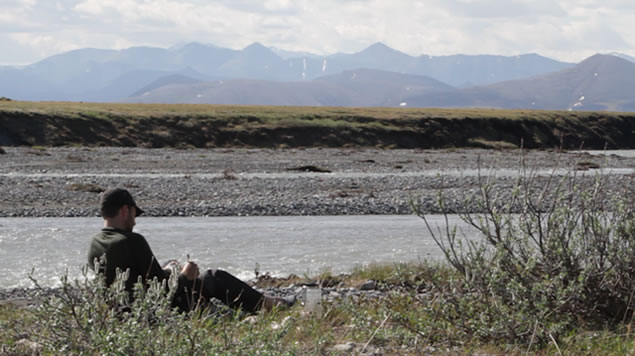 photo of Jason writing next to an arctic river